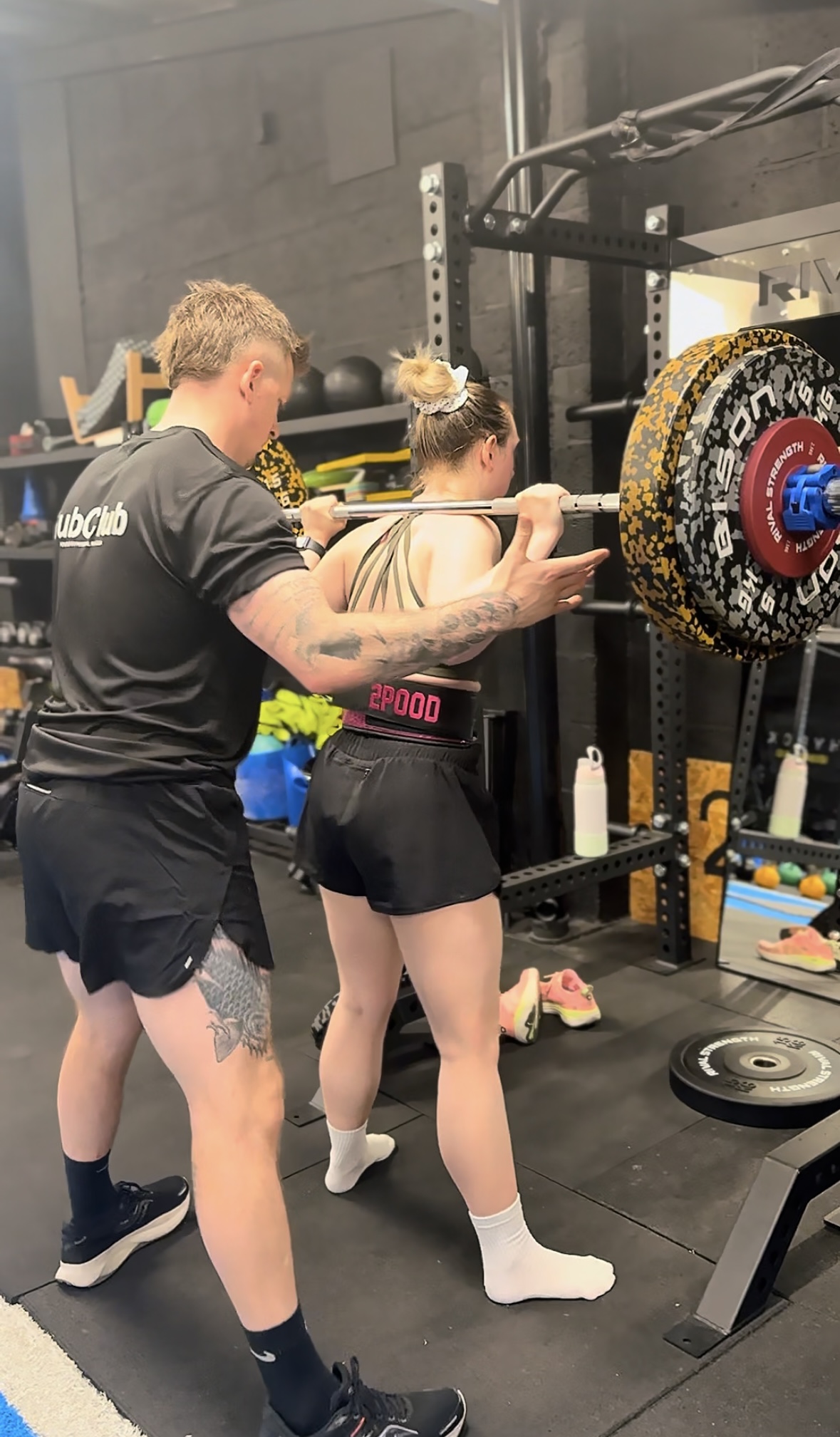 Coach spotting a member on the back squat